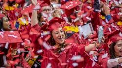 graduate holds cell phone to take selfie amid a flurry of confetti